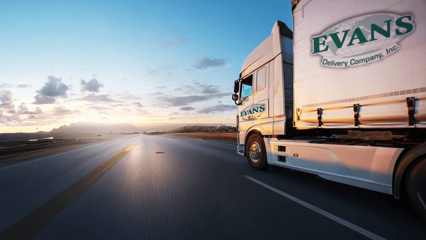 White EVANS delivery truck driving on a road at sunset